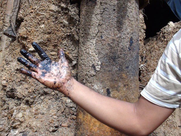 Morador mostra mão melada de petróleo (Foto: Lílian Marques/G1 BA)