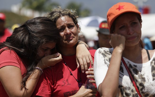Mulheres choram enquanto assistem em telão ao funeral de Estado do presidente Hugo Chávez (Foto: AP)